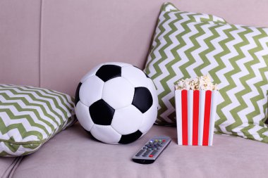 Futbol topu, uzaktan kumanda ve patlamış mısır rahat kanepe kapalı