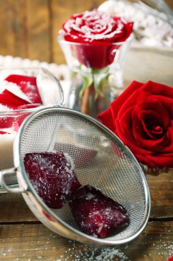 Gül çiçek yaprakları yumurta akı ve şeker, ahşap arka plan üzerinde şekerlenmiş yapmak