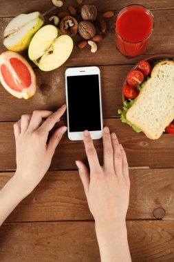 Gıda ve ahşap arka plan üzerinde eller içinde hareket eden telefon