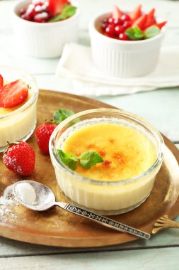 Creme brulee tatlı taze çilek ve renk ahşap zemin üzerine nane yaprakları ile