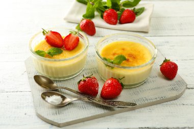 Creme brulee tatlı taze çilek ve renk ahşap zemin üzerine nane yaprakları ile