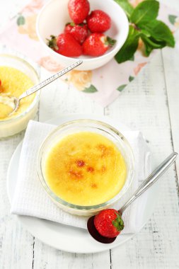Creme brulee tatlı taze çilek ve renk ahşap zemin üzerine nane yaprakları ile