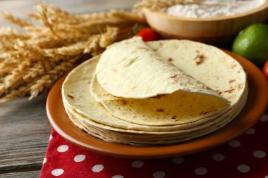 ev yapımı kepekli un tortilla ve ahşap masa arka plan üzerinde plaka üzerinde sebze yığını