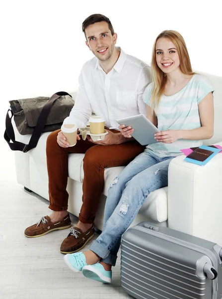Portret młodego szczęśliwa para z bagażem, siedząc na kanapie. na białym tle — Zdjęcie stockowe