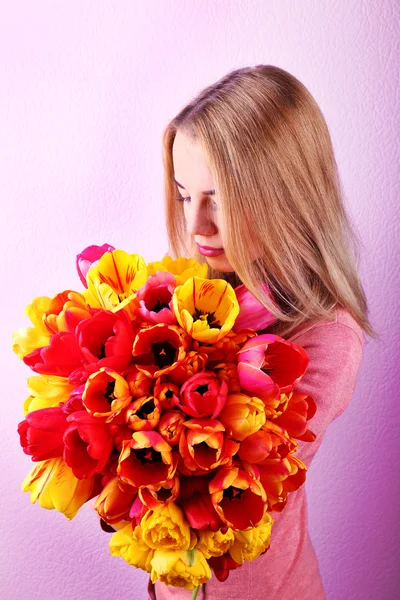 Retrato de jovem com belo buquê de tulipas no fundo do papel de parede — Fotografia de Stock