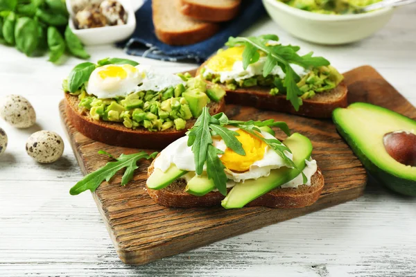 Sanduíches saborosos com ovo, abacate e legumes em fundo de madeira — Fotografia de Stock