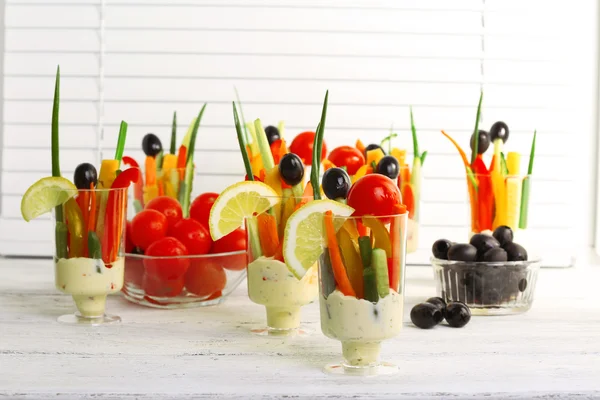 Snack of vegetables in glassware on wooden table on blinds background — Stock Photo, Image