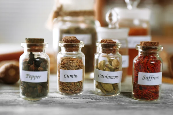 Assortiment van specerijen in glazen flessen op houten achtergrond — Stockfoto