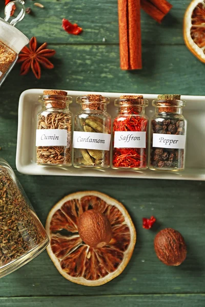 Assortment of spices in glass bottles on wooden background — Stock Photo, Image