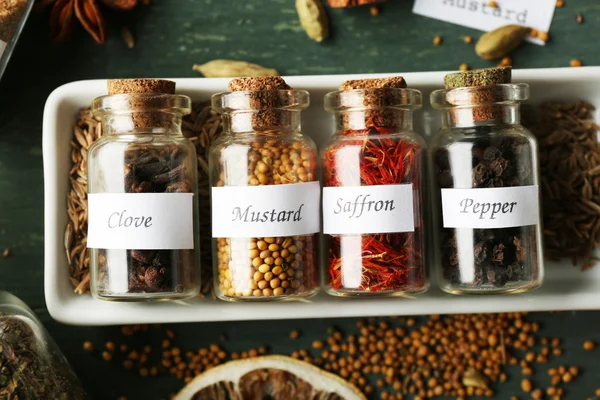 Assortment of spices in glass bottles on wooden background — Stock Photo, Image