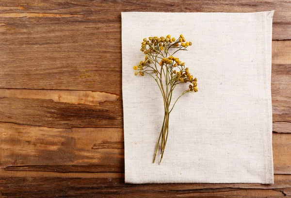 Beautiful dry flowers on napkin on wooden background — Stock Photo, Image