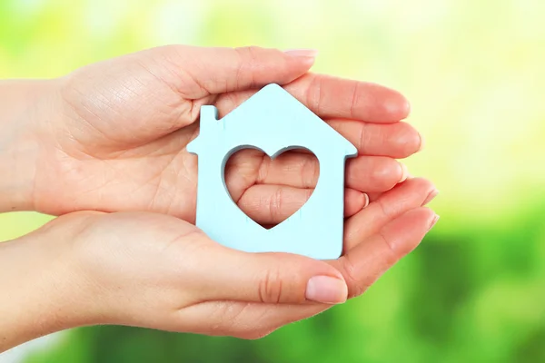 Female hands holding model of house on bright background — Stock Photo, Image