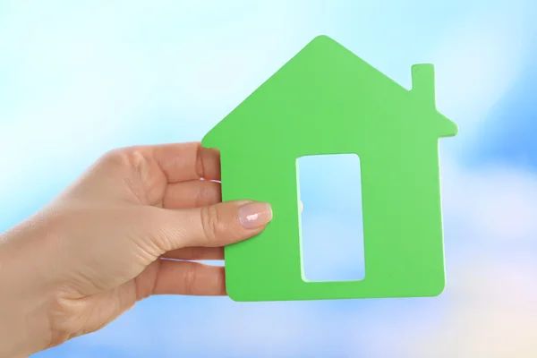 Female hand holding model of house on bright background — Stock Photo, Image