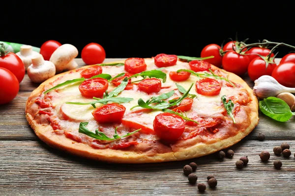 Läcker pizza med ost och körsbärstomater på träbord på mörk bakgrund — Stockfoto