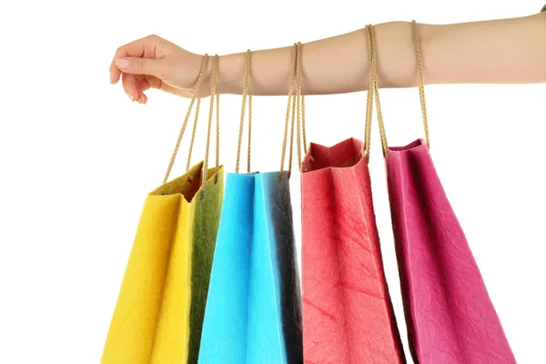 Mano femminile con colorati sacchetti di carta per la spesa isolati su bianco — Foto Stock