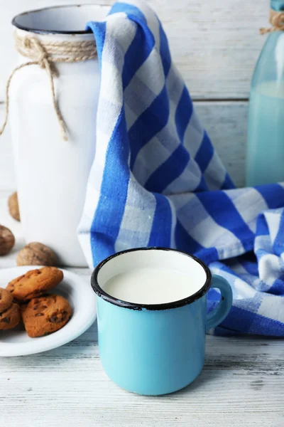 Milch im Becher mit Walnüssen und Keksen auf hölzernem Hintergrund — Stockfoto