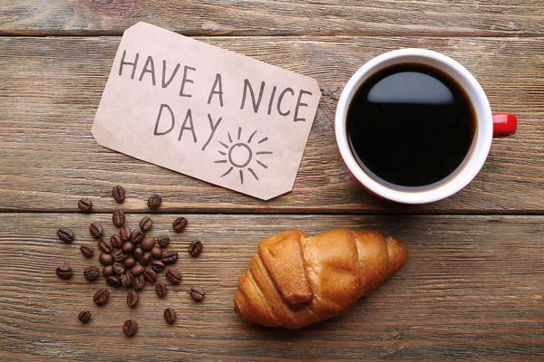 Cup of coffee and fresh croissant on wooden table, top view — Stock Photo, Image