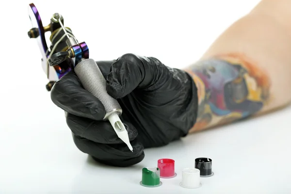 Hand of tattoo artist with tattoo machine and colorful ink isolated on white — Stock Photo, Image