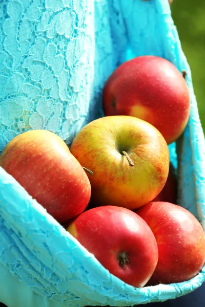 Red apple in hemline of female clothing, closeup — Stock Photo, Image