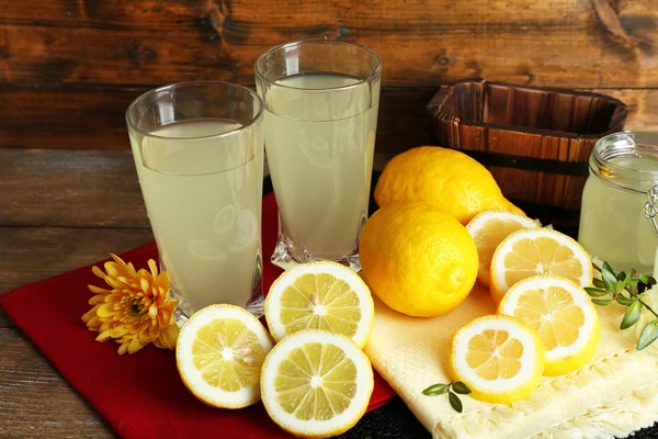 Stillleben mit Zitronensaft und Zitronenscheiben auf Holzgrund — Stockfoto