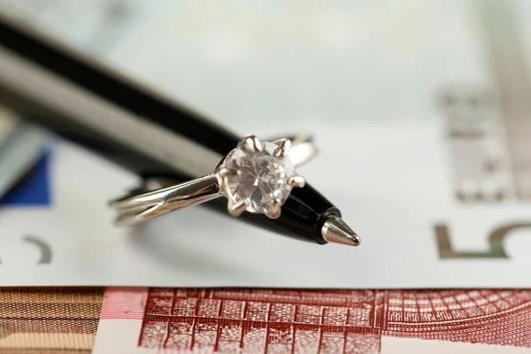 Anello nuziale su penna, su sfondo di banconote. Matrimonio di convenienza — Foto Stock