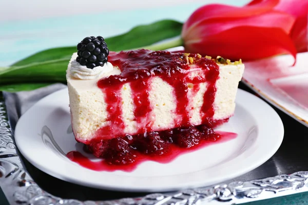 Pedaço saboroso de cheesecake com molho de baga na placa na mesa de perto — Fotografia de Stock