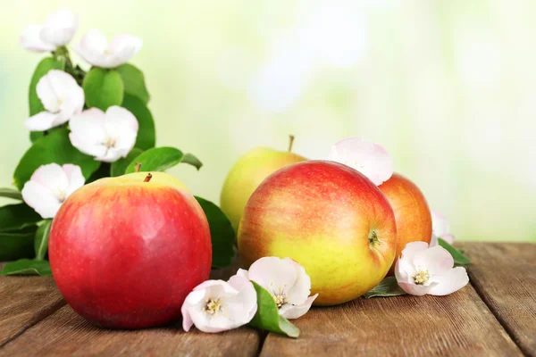 Manzanas frescas con flor de manzana sobre mesa de madera, sobre fondo natural —  Fotos de Stock