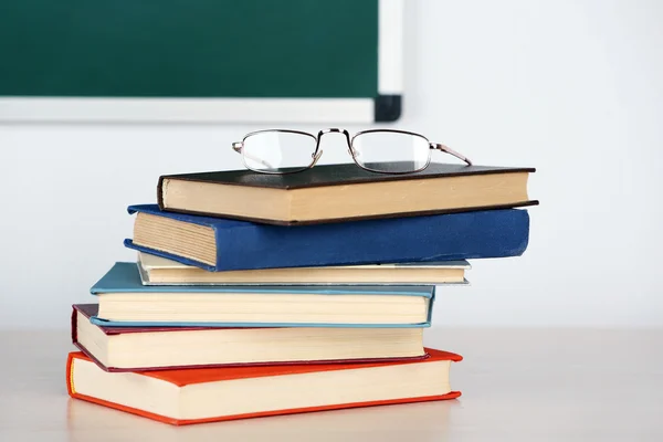 Hoop boeken en bril op tabel in de klas — Stockfoto