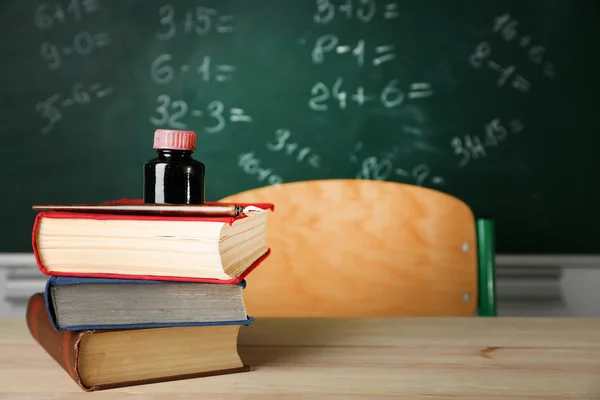 Högen med böcker på skrivbord, på blackboard bakgrund — Stockfoto