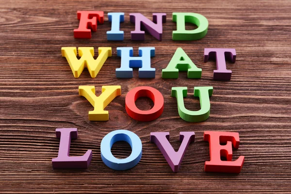 Napis znaleźć to, co kochasz wykonane z kolorowych liter na drewniane tła — Zdjęcie stockowe