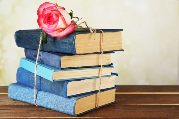 Gebonden boeken met roze roos op houten tafel, close-up — Stockfoto