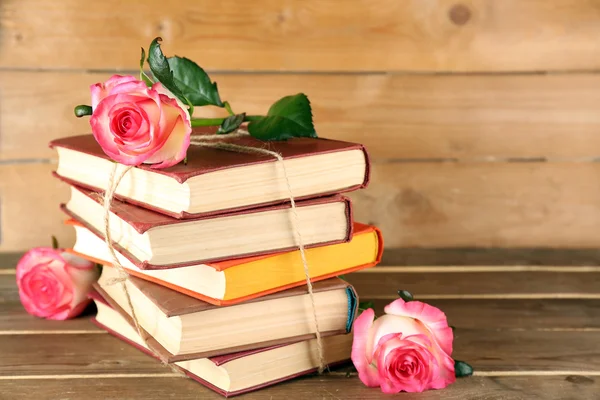Livros amarrados com rosas cor-de-rosa em fundo de madeira — Fotografia de Stock