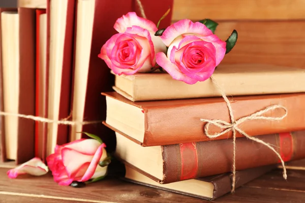 Livros amarrados com rosas rosa na mesa de madeira, close-up — Fotografia de Stock