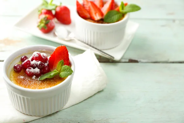 Creme Brulee Dessert mit frischen Erdbeeren auf Serviette, auf farbigem Holzhintergrund — Stockfoto