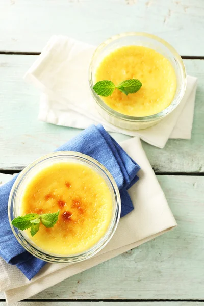 Crema brulee dessert su tovagliolo, su sfondo di legno a colori — Foto Stock