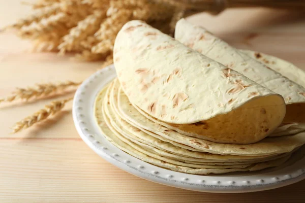 Stack of homemade whole wheat flour tortilla on plate, on wooden table background — Stock Photo, Image