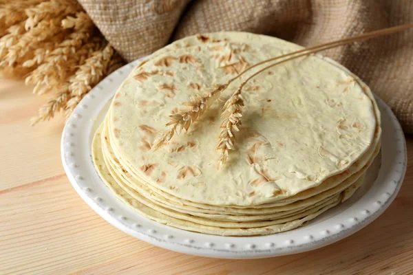 Pilha de tortilla de farinha de trigo integral caseira na placa, no fundo da mesa de madeira — Fotografia de Stock