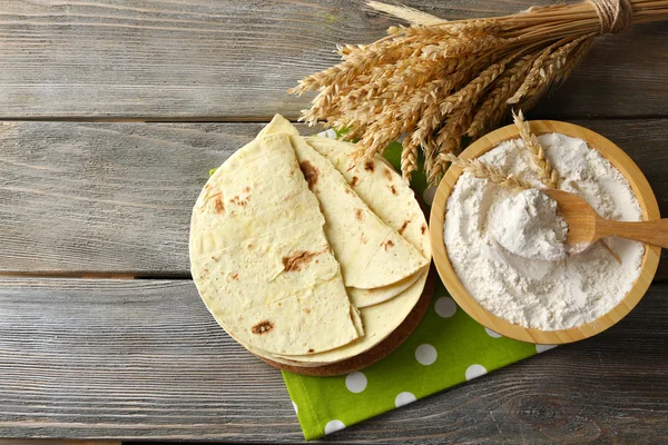 Stack of homemade whole wheat flour tortilla on cutting board, on wooden table background — Stock Photo, Image