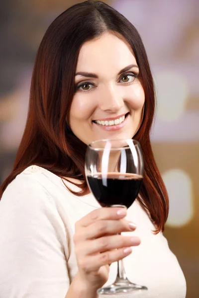 Mujer joven degustación de vino sobre fondo brillante Imagen de stock