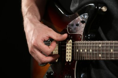 Genç adam elektro gitarla oynuyor. Yakın plan.