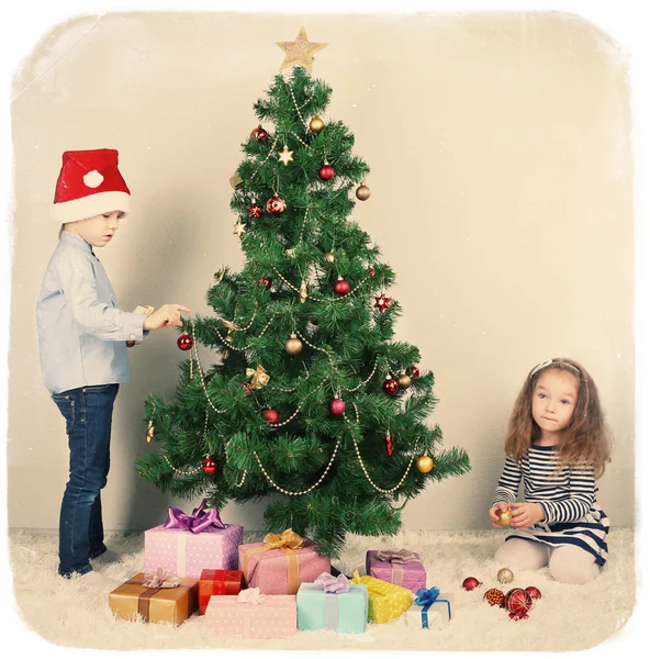 Kids decorating Christmas tree with baubles in room — Stock Photo