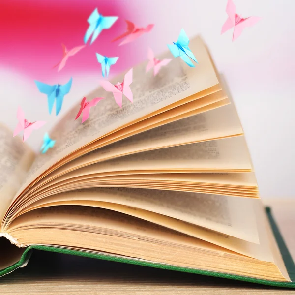 Open book on table and paper butterflies — Stock Photo, Image