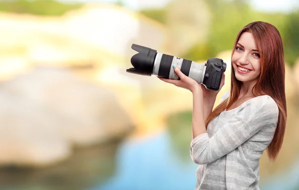 Молодая женщина фотограф делает фотографии на фоне природы — стоковое фото