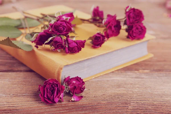 Rosas secas con libro sobre mesa de madera, primer plano — Foto de Stock