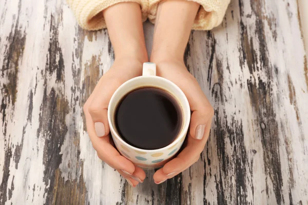 Female hands holding cup of coffee on wooden background — Stock Photo, Image