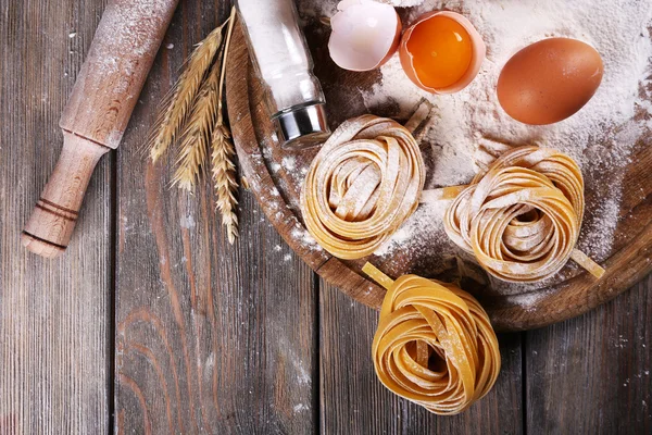 RAW hemgjord pasta och ingredienser för pasta på trä bakgrund — Stockfoto