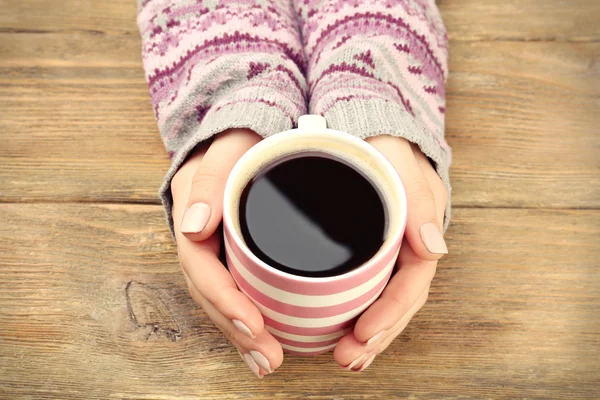 Female hands holding cup of coffee on wooden background — Stock Photo, Image