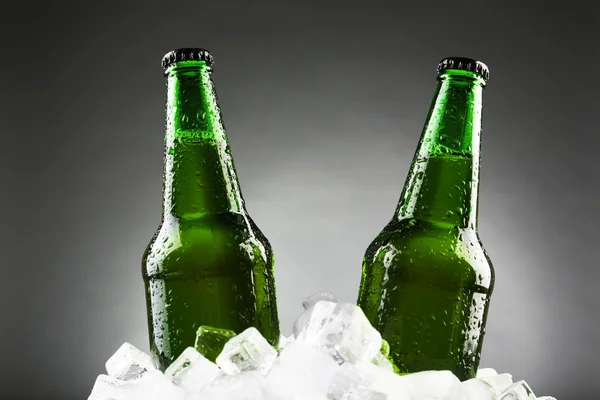 Bottiglie di vetro di birra in cubetti di ghiaccio su sfondo colore — Foto Stock