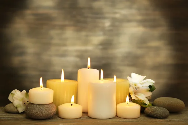 Nádherná skladba se svíčkami a wellness kameny na dřevěné pozadí — Stock fotografie