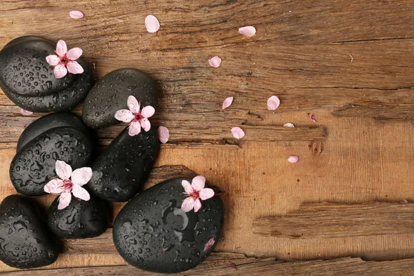 Wellness-Steine mit Frühlingsblumen auf dem Tisch aus nächster Nähe — Stockfoto